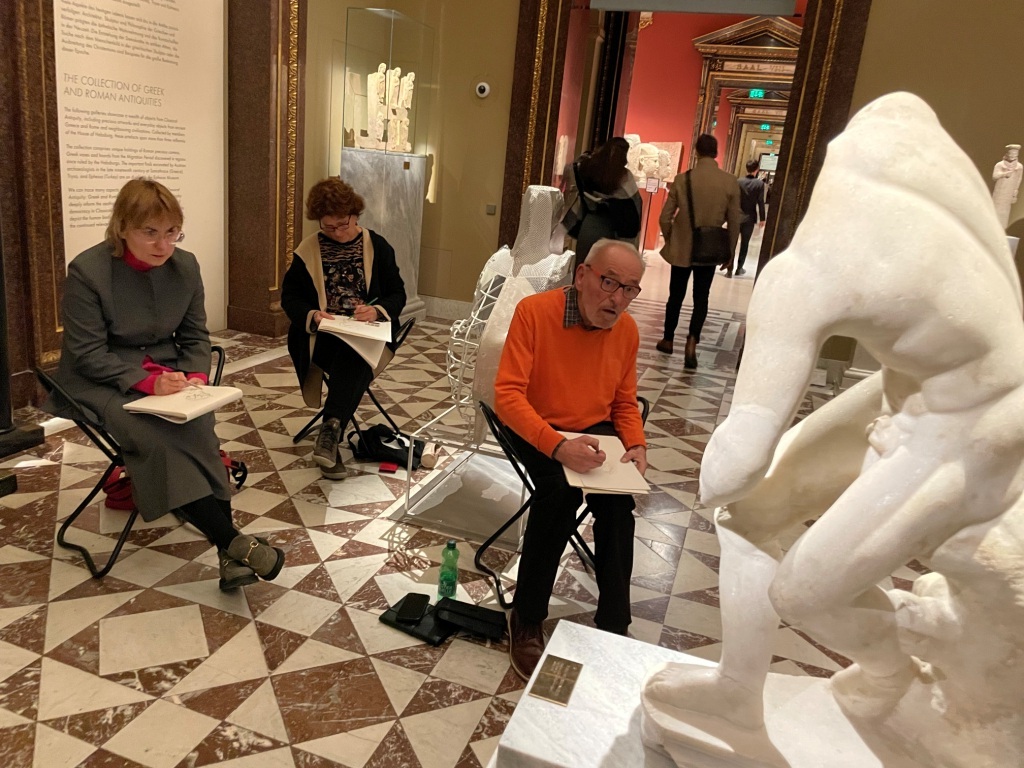 Personen zeichnen eine antike Skulptur im Museum